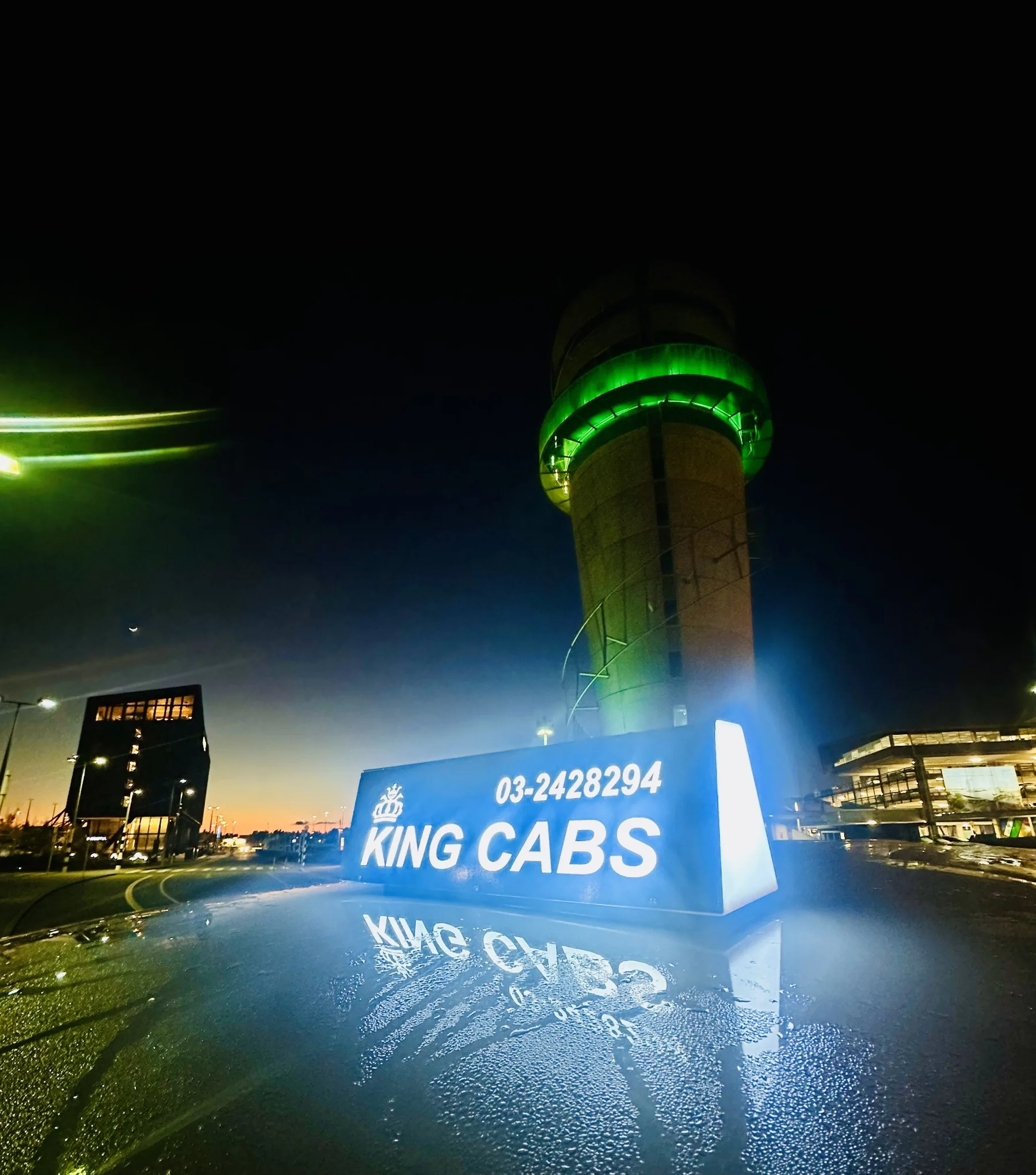 Original King Cabs illuminated roof sign showing King Cabs and 03-2428294 with Christchurch Airport tower behind it at night