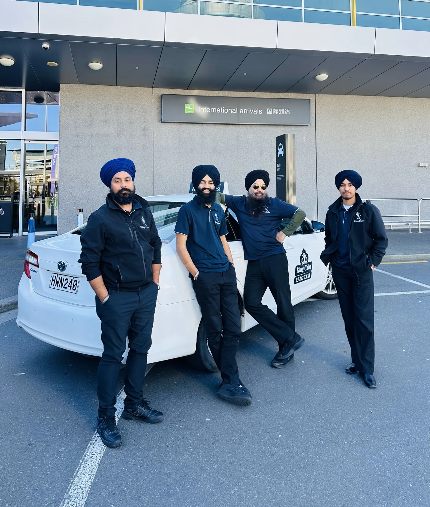 King Cabs uniformed drivers beside their branded taxi at Christchurch Airport international arrivals